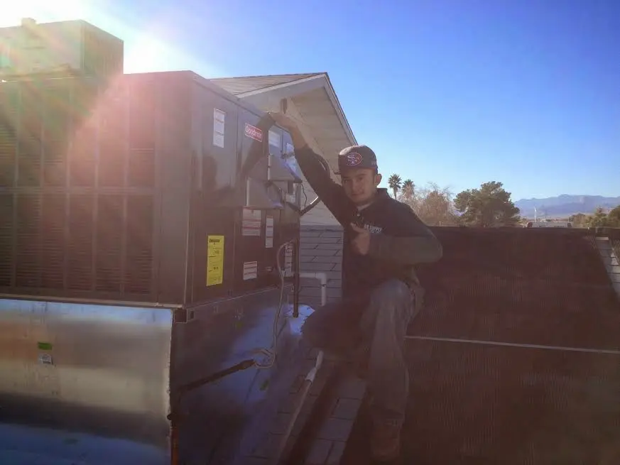 HVAC technician performing Air Duct Cleaning on a rooftop unit in Lawrenceburg